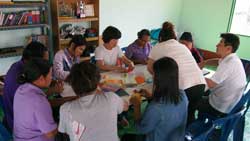 現地で日本の折り紙を講習する講師と熱心に折り方を学ぶ現地保育所の先生たち